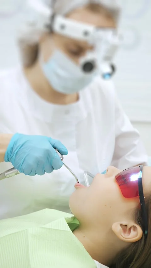 Close-up of the dentists hand treating teeth of a little girl in clinic. Video stock 317797325