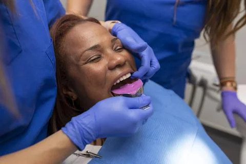 Close up of a dentist's hands placing an impression tray at the dental clinic Stock Photos
