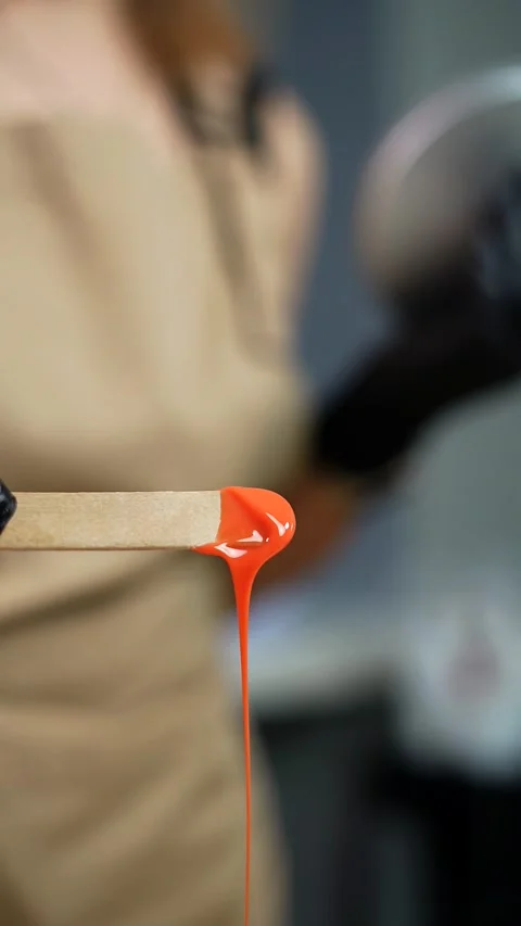 Close-up of depilation master hands holds spatula with melted wax. 9:16 Video stock 233826019