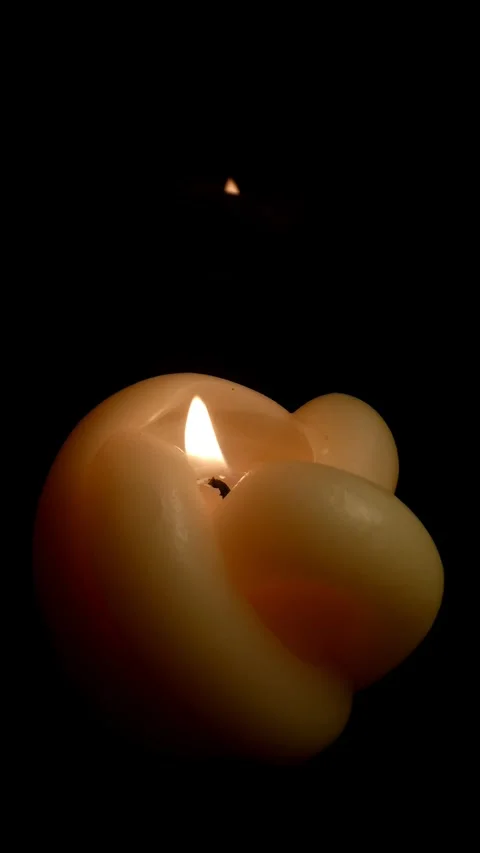 Close-up of a designer knot candle being blown out in total darkness Stock Footage 331099862