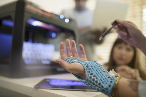 Close up designer trying on prototype glove at 3D printer Stock Photos