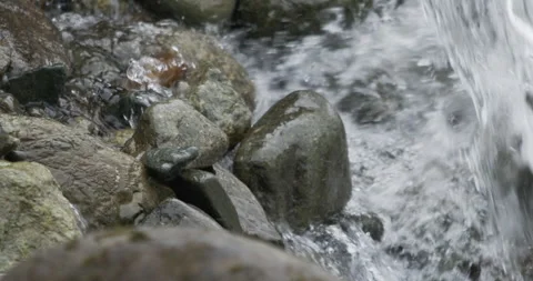 Close up detail of river water current flowing through river rocks in slow Stock Footage 240950488