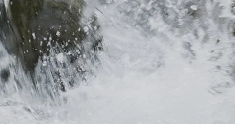 Close up detail of river water current flowing through river rocks in slow Video stock 240950831