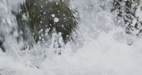 Close up detail of river water current flowing through river rocks in slow Stock Footage 240950985