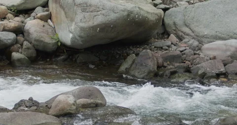 Close up detail of river water current flowing through river rocks in slow Stock Footage 240951535