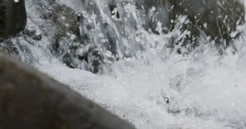 Close up detail of river water current flowing through river rocks in slow Stock Footage 240952269