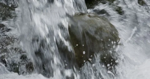 Close up detail of river water current flowing through river rocks in slow Stock Footage 240953728