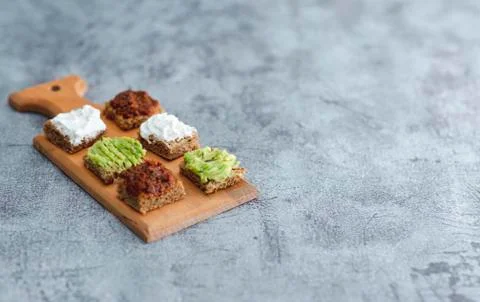 Close up detail view of bread bites with colorful tapas over rustic backdrop  Photos