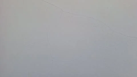 Close-up of detailed cracking patterns on a weathered white plaster wall Stock Photos