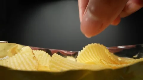 Close-up details of picking up crispy potato chips from a bag Stock Footage 244801570