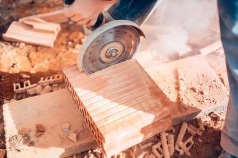 Close-up details of worker using angle grinder for cutting bricks Stock Photos