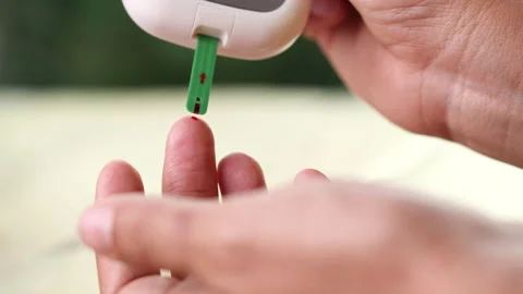 Close up diabetic test using lancet pen ad glucometer on finger with blood drop Stock Footage 156480853