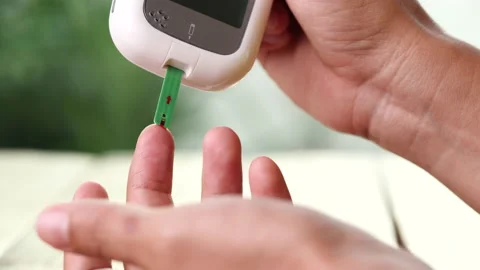 Close up diabetic test using lancet pen ad glucometer on finger with blood drop Stock Footage 156480857