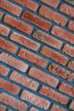 Close up diagonal front angle view of cracked weathered red brick wall. Stock Photos