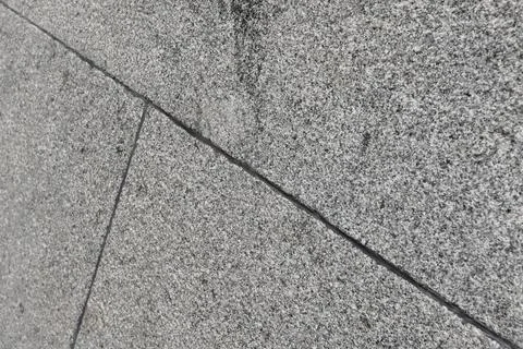 Close-up of diagonal granite tile texture on a gray stone wall showing seams Stock Photos