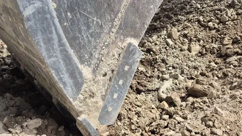 Close-up diagonal shot of an excavator bucket scooping and pulling soil 스톡 동영상 344030964