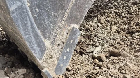 Close-up diagonal shot of an excavator bucket scooping soil – Slow Motion Video stock 344030973