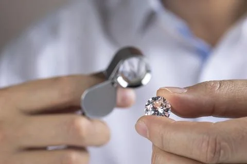 Close up of diamond expert's hand at workplace evaluating gemstones polished Stock Photos