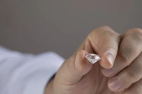 Close up of diamond expert's hand at workplace evaluating gemstones polished Stock Photos