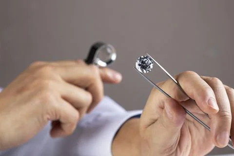 Close up of diamond expert's hand at workplace evaluating gemstones polished Stock Photos