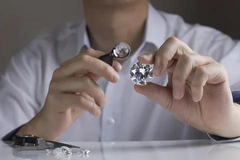 Close up of diamond expert's hand at workplace evaluating gemstones polished Stock Photos