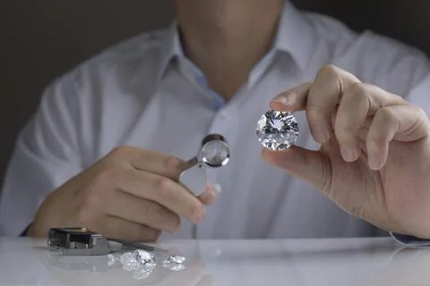 Close up of diamond expert's hand at workplace evaluating gemstones polished Stock Photos
