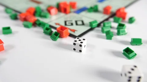 Close up of dice spinning onto a board game of moving red and green house  Stock Footage 89188239