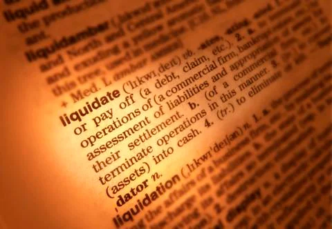 CLOSE UP OF DICTIONARY PAGE SHOWING DEFINITION OF THE WORD LIQUIDATE Stock Photos