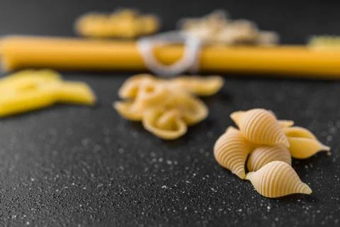 Close up of different dry pasta types against black background. Stock Photos