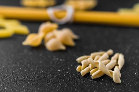 Close up of different dry pasta types against black background. Stock Photos