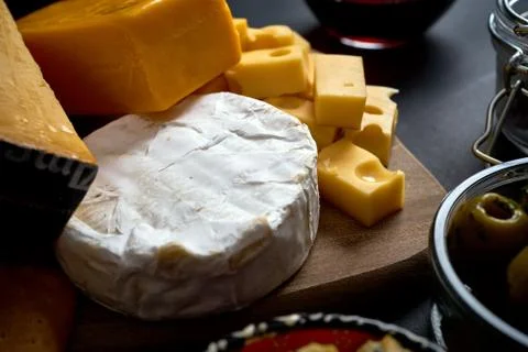 Close up on different kinds of cheese on wooden board on black table Stock Photos