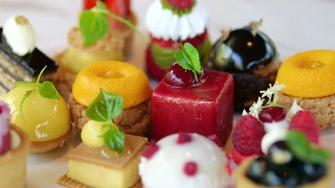 Close-up of different small cakes with original flavors, fruit pieces on a white Video stock 217664369
