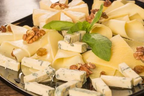 Close up with different types of cheese, on a black plate Stock Photos