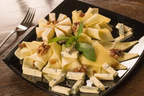 Close up with different types of cheese, on a black plate Stock Photos