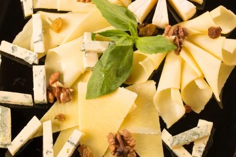 Close up with different types of cheese, on a black plate Stock Photos