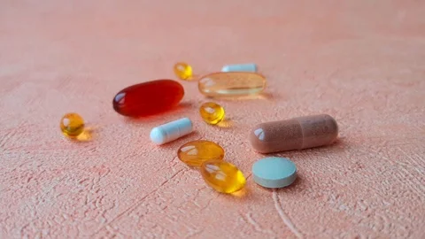 Close-up: different types of pills. Female hand takes brown pill. Stock Footage 103857440