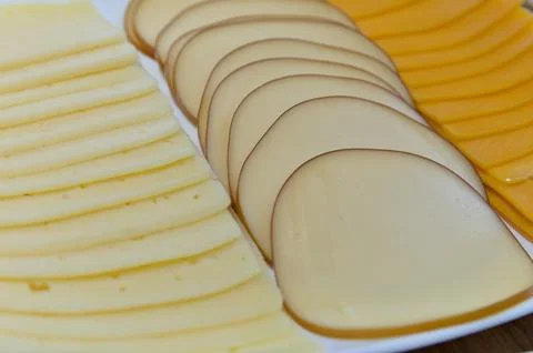 Close up different types of slices of cheese on white plate. top view Foto stock