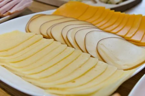 Close up different types of slices of cheese on white plate Stock Photos