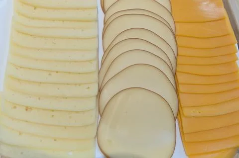 Close up different types of slices of cheese on white plate. top view Stock Photos