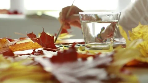 Close-up of the diffusion of yellow paint in drawing water with autumn leaves ag Stock Footage 80558469