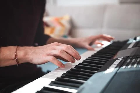Close-up of a digital keyboard with a hand playing a melody, illuminated by s Photos