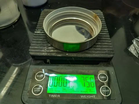 A close up of a digital scale displaying a weight of 75,8 grams with a meta.. Stock Photos