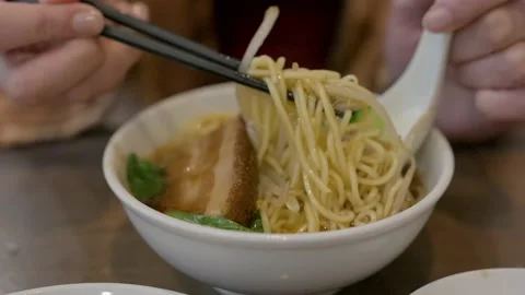 Close up diner scooping up pork lo mein with broth Stock Footage 228998811