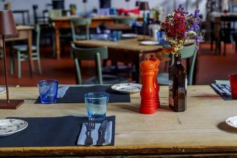 Close-up dining table with blue glasses, red pepper grinder, and wildflower.. Stock Photos