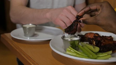 Close up dipping chicken wings in ranch hot buffalo sauce on wings man and wo Stock Footage 89364000