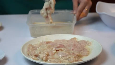 Close Up of Dipping Raw Chicken Fillet into Liquid Batter with Tongs 스톡 동영상 334324239