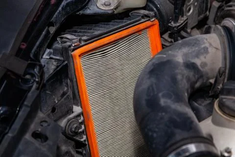 Close-up on a dirty air filter for an engine with an orange frame installed i Fotos de archivo