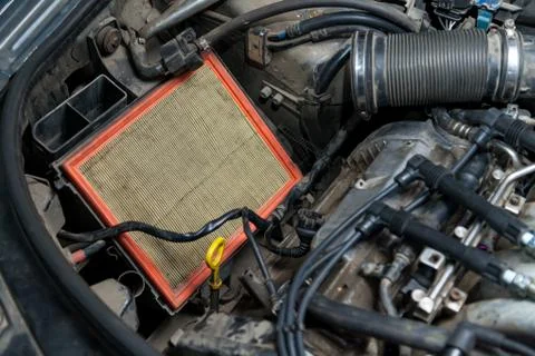 Close-up on a dirty air filter for an engine with an orange frame installed i Fotos de archivo