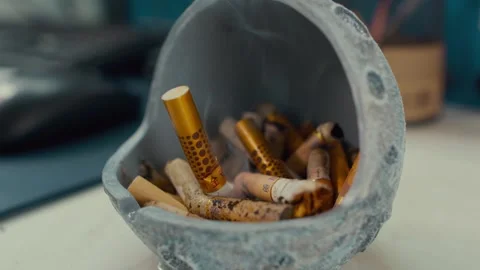 Close-up of Dirty Ashtray with Used Cigarette Butts on Desk Video stock 336545409