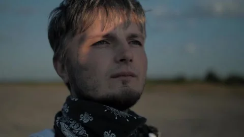 Close up dirty guy with a bandana looking at the sunset into the distance Stock Footage 137845341